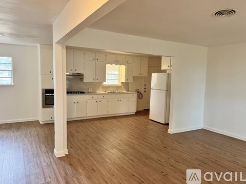 A kitchen with white cabinets and a wooden floor.
