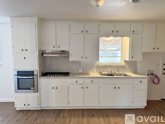A kitchen with white cabinets and a stainless steel oven.