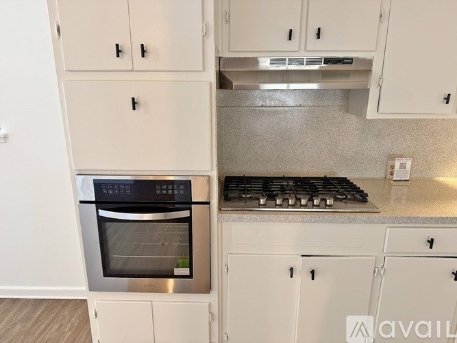 A modern kitchen with white cabinets and a stainless steel oven and stove.