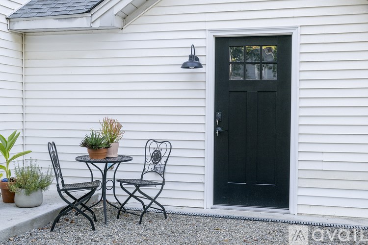 A black door is on the side of a white house.