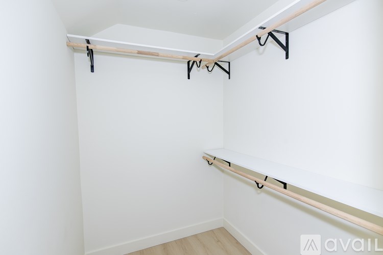 A white wall with a wooden beam and black hooks.