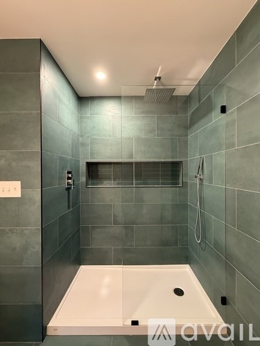 A bathroom with a white tub and a grey tile wall.