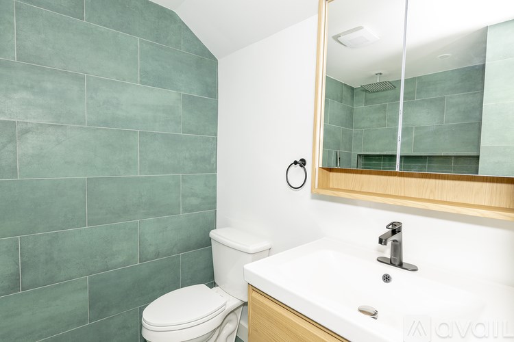 A bathroom with a toilet, sink, and mirror.