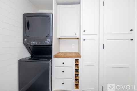 A black microwave oven is on a black fridge in a kitchen.