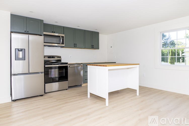 A kitchen with a white island and stainless steel appliances.