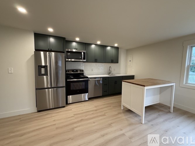 A room with wooden flooring and three windows.