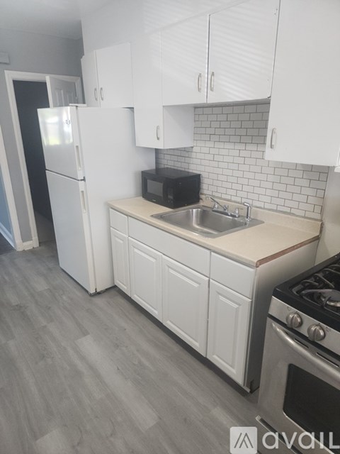 A kitchen with white cabinets and a stainless steel sink and stove.