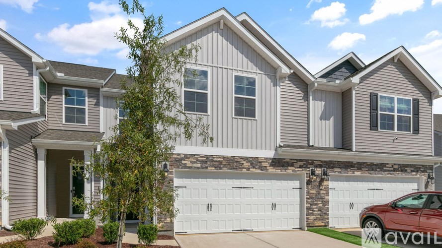A house with a garage and a tree in front of it.