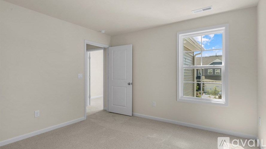 A room with a white door and a window showing a view of a house.