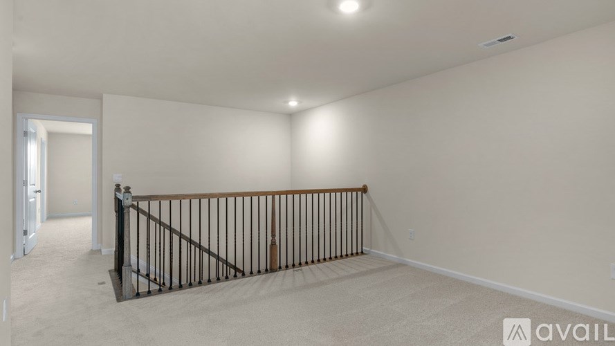 A room with a railing and a doorway leading to another room.