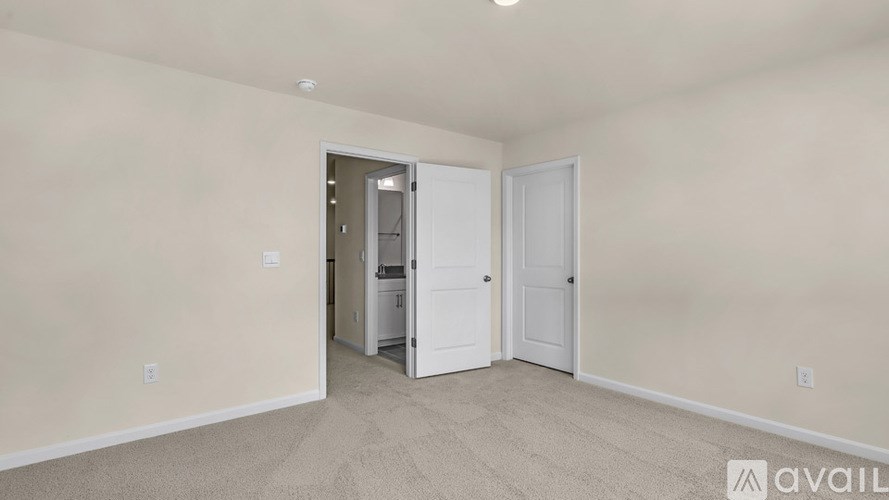 A room with a carpeted floor and a doorway leading to another room.