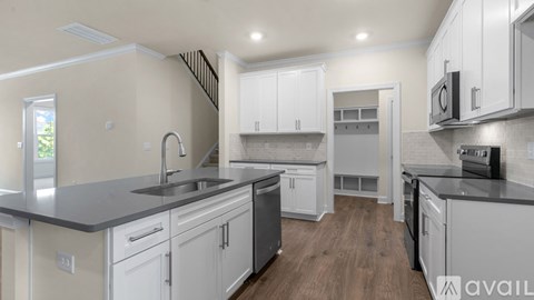 A modern kitchen with white cabinets and a wooden floor.