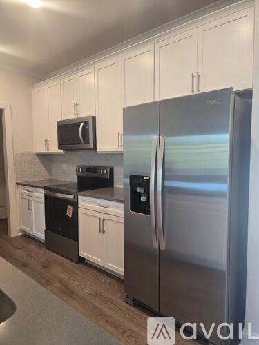 A kitchen with a stainless steel refrigerator and white cabinets.