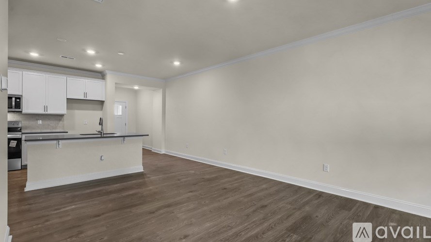 A spacious kitchen and living room with wooden flooring and white walls.