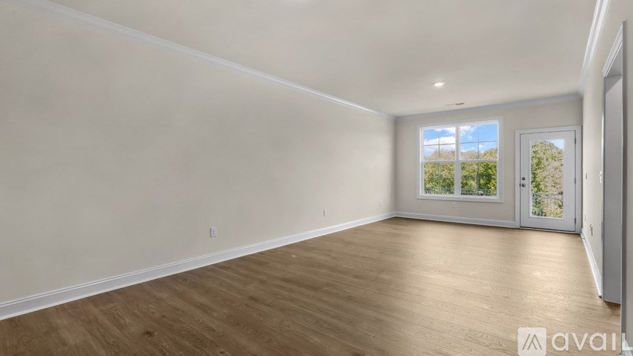 A room with wooden flooring and a sliding glass door leading to a balcony.