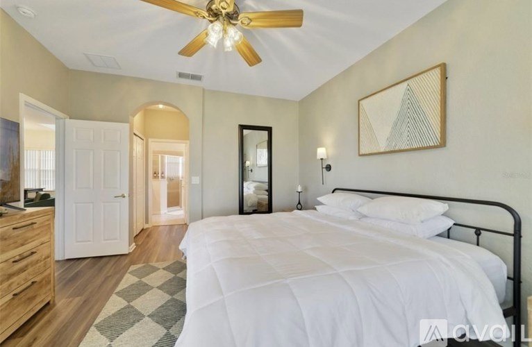 A bedroom with a large bed, a ceiling fan, and a mirror.