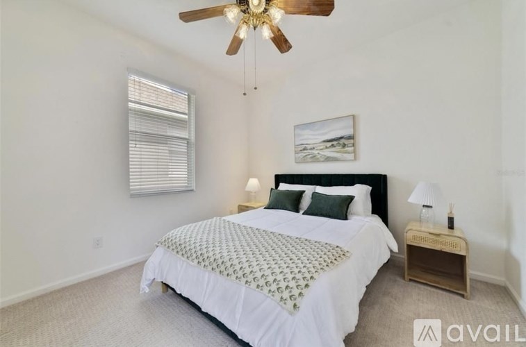 A bedroom with a large bed and a ceiling fan.