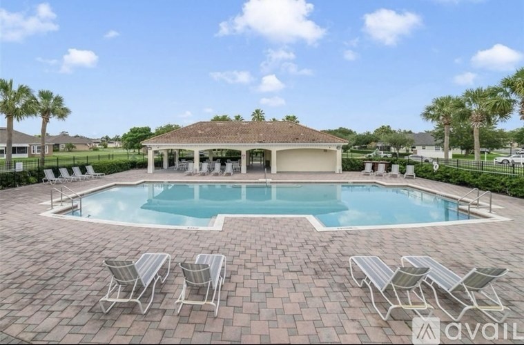 A pool with a pavilion and chairs around it.