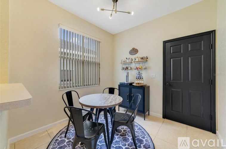A room with a round table and chairs, a ceiling fan, and a black door.