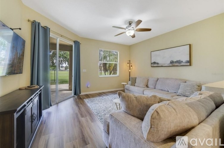 A living room with a grey couch and a ceiling fan.