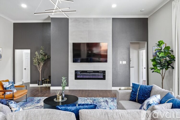 A modern living room with a grey couch, a black coffee table, and a large TV mounted on the wall.