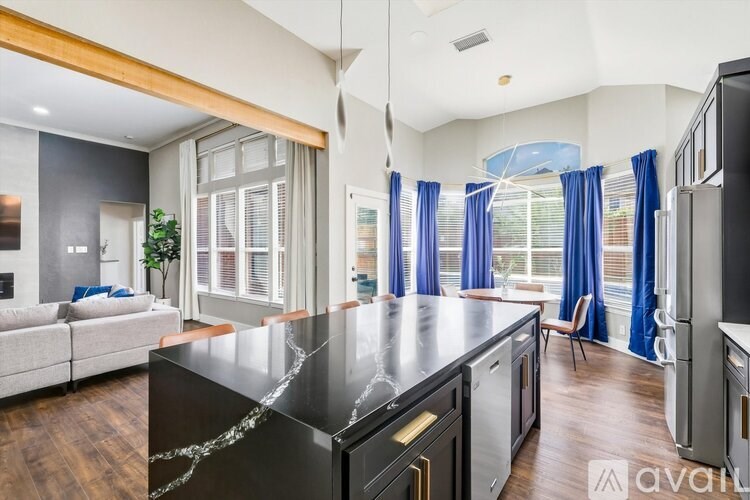 A modern kitchen with a black countertop and stainless steel appliances.