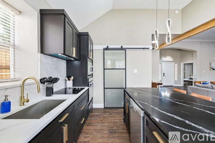 A kitchen with black cabinets and a marble countertop.