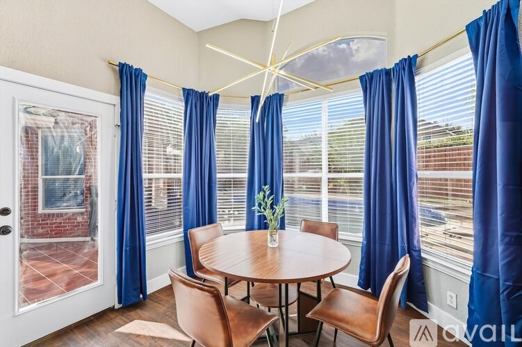 A dining room with a round table and blue curtains.