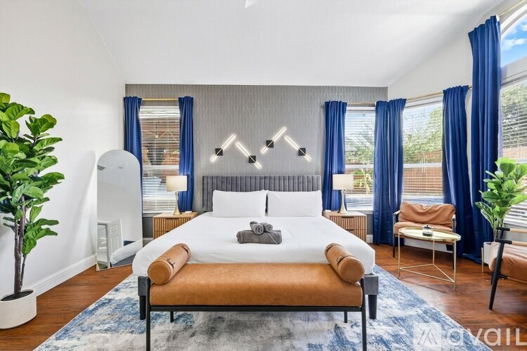 A bedroom with a large bed and a chair.