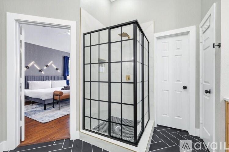 A white door is open to a room with a bed and a white wall.