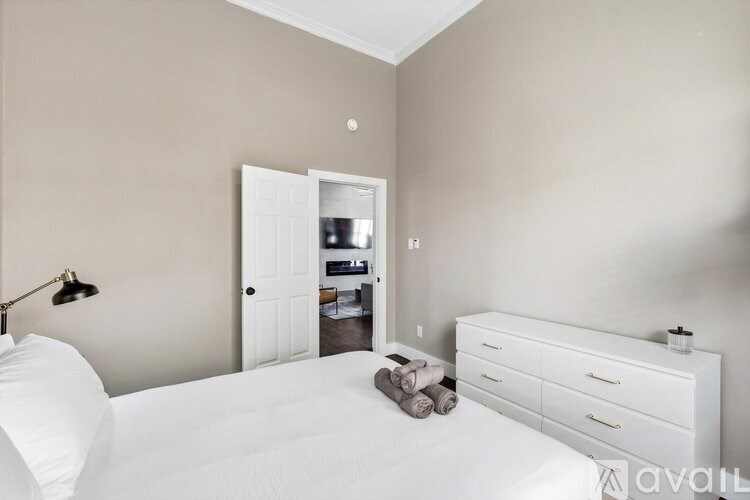 A bedroom with a white bed, dresser, and a small closet.