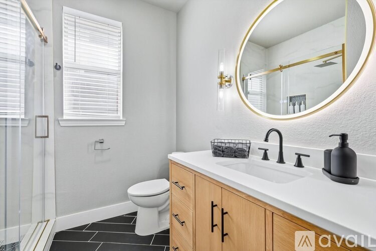 A bathroom with a white toilet, a round mirror, and a wooden cabinet.