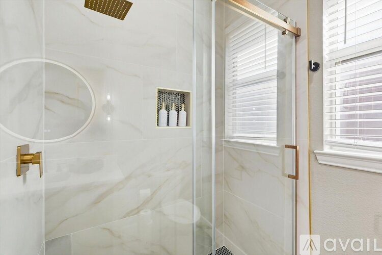 A bathroom with a marble wall and a glass shower door.
