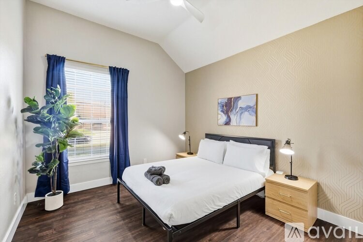 A bedroom with a bed, nightstand, and a plant.