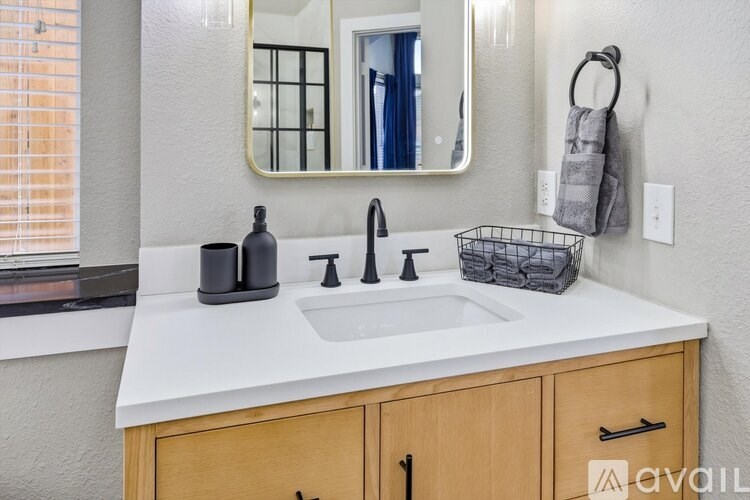 A bathroom with a white countertop and a mirror above the sink.