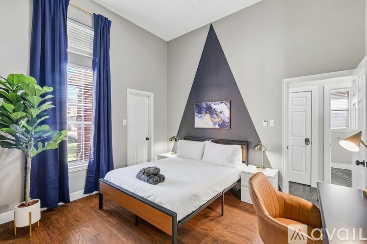 A bedroom with a bed, chair, and a potted plant.