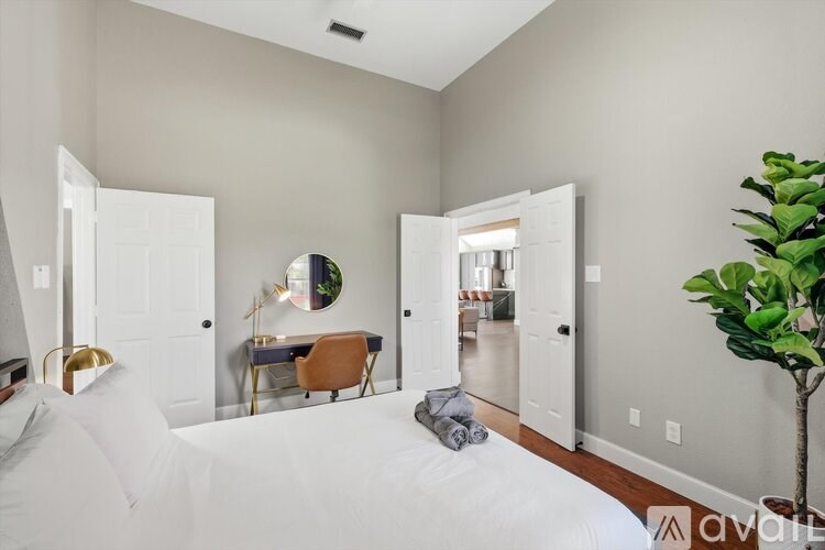 A bedroom with a large bed and a desk with a chair.