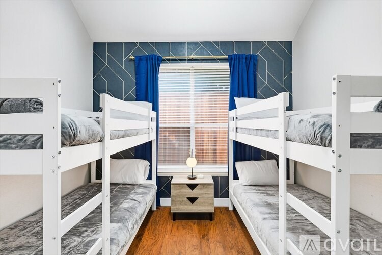 Three bunk beds in a room with blue curtains.