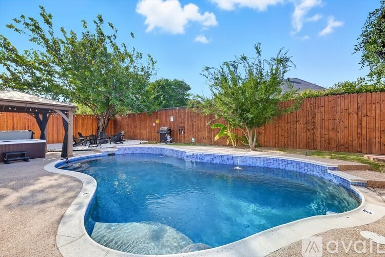 A small residential pool with a wooden fence and a hot tub.