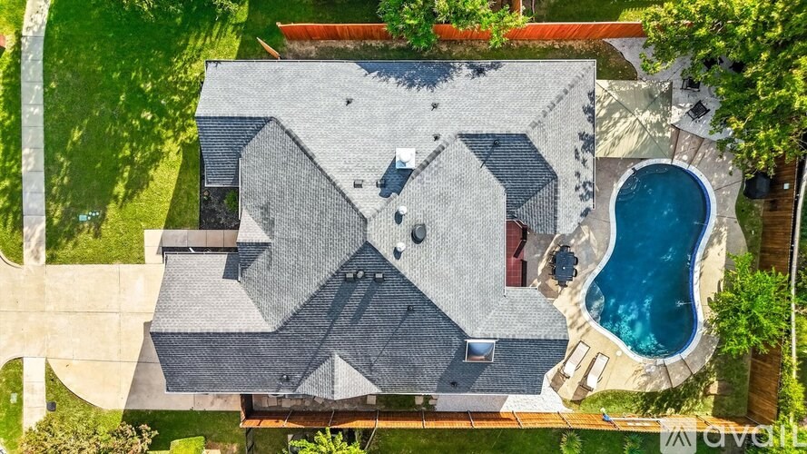 A house with a grey roof and a blue pool.