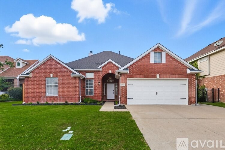 A red brick house with a white garage door and a driveway leading to the front door.