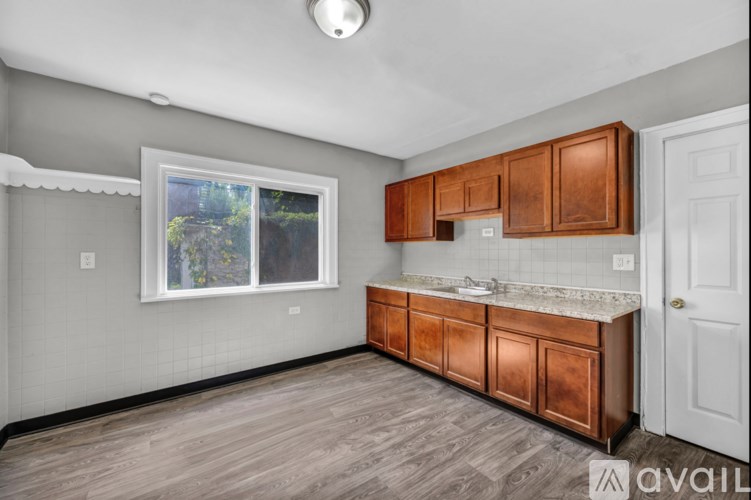 A kitchen with wooden cabinets and a window showing greenery outside.