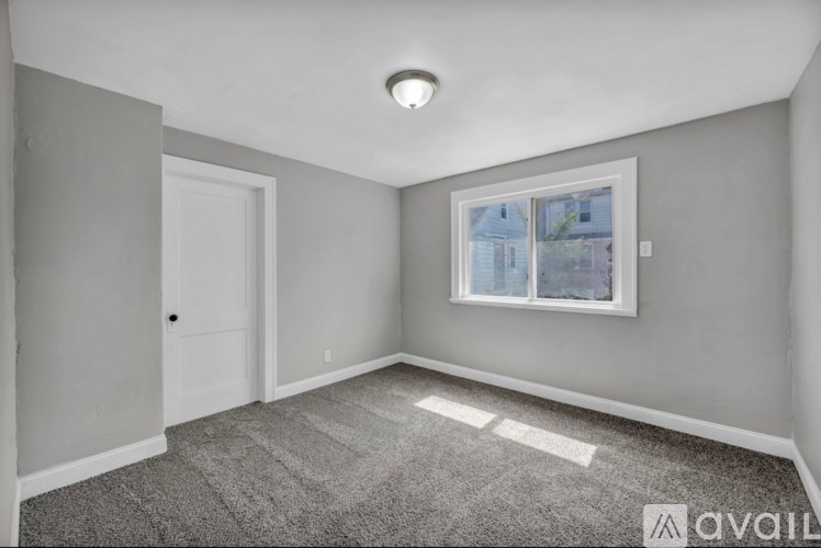 A room with a carpeted floor, a window, and a door.