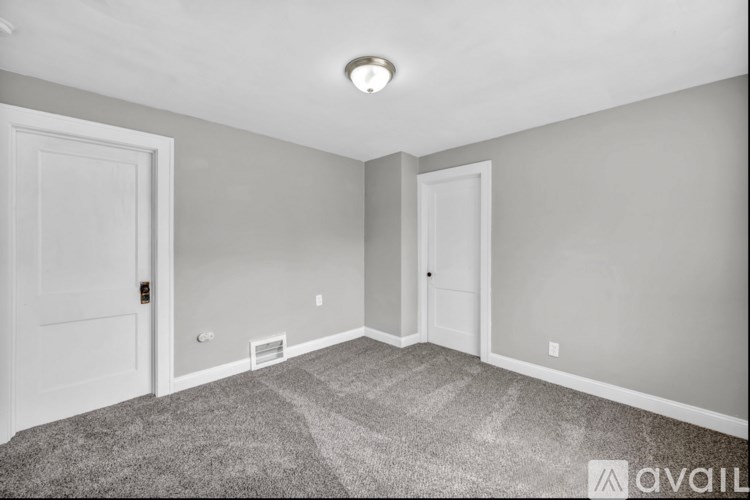 A room with a carpeted floor and two doors.