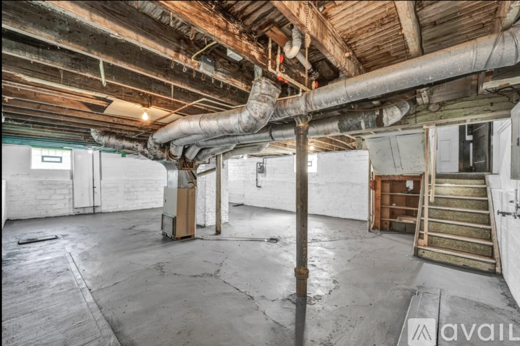 A large, empty room with a complex network of pipes on the ceiling.
