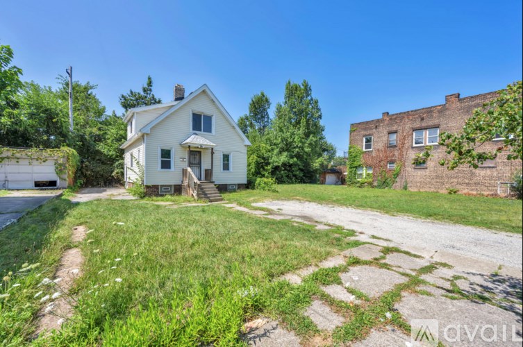A white house with a porch and a tree in front of it.