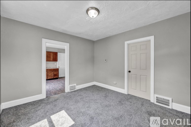 A room with a carpeted floor and two doors, one of which is open.