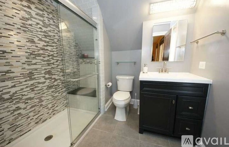 A bathroom with a stone wall and a glass shower.