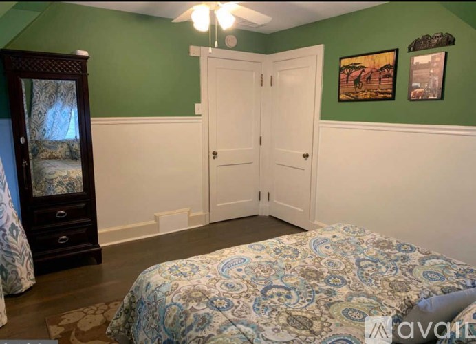 A bedroom with a bed, a dresser, and two pictures on the wall.