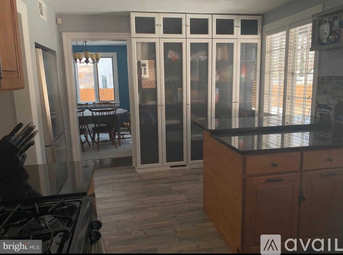 A kitchen with a stove top oven and a dining area in the background.